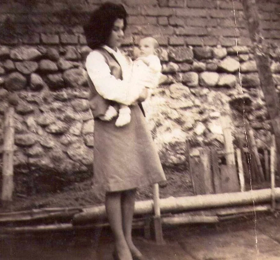 Dolly con Nelson bebé en brazos, frente a un muro de piedra, 1965
