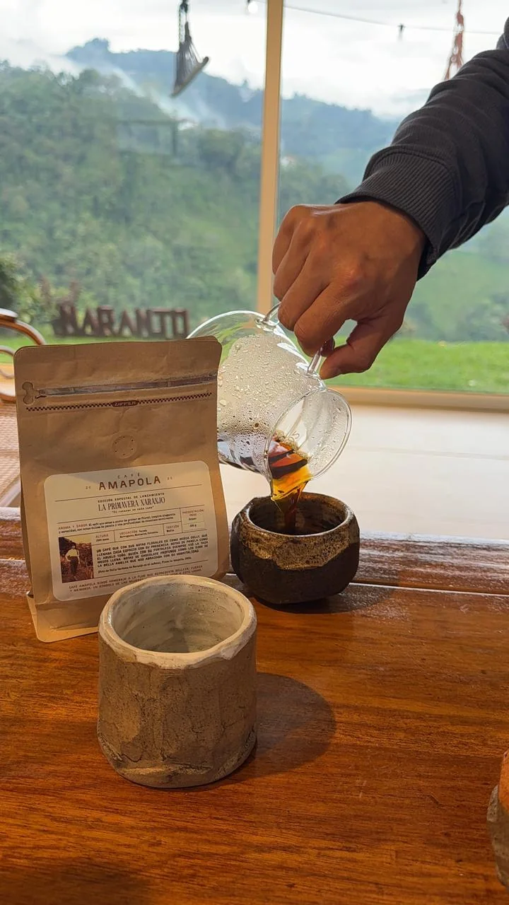 La Primavera Naranjo servida en una taza de cerámica, junto a su bolsa, con las montañas al fondo